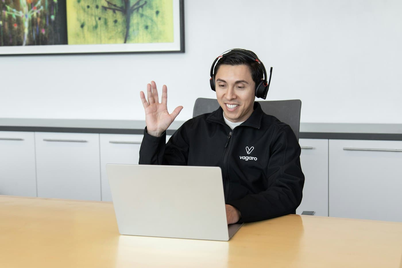 Smiling call centre agent wearing a headset at a laptop