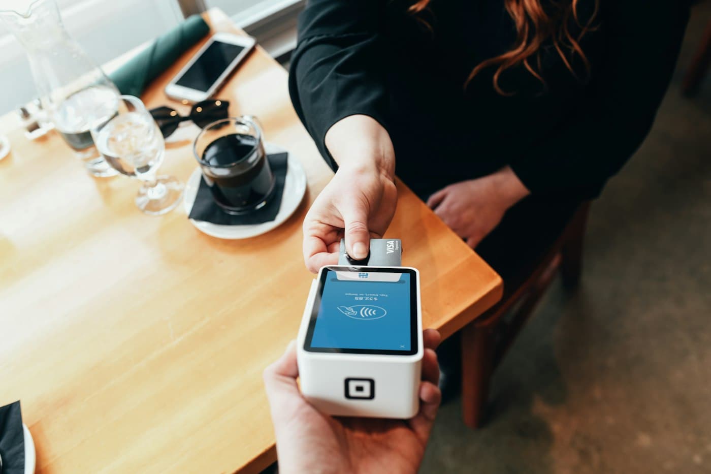 Café staff taking a card payment on a handheld card terminal